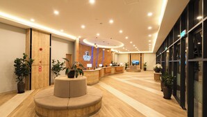 A modern hotel lobby with a reception desk, seating area, and potted plants. - Zenith Suites Cameron (Tanah Rata)