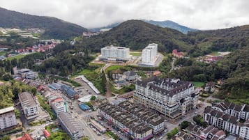 An aerial view of a town with a mix of modern and traditional buildings, roads, and surrounding greenery.
