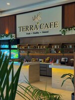 Il Caffè Terra, con interni moderni, presenta un'ampia insegna, pannelli in legno e diversi oggetti decorativi sugli scaffali.