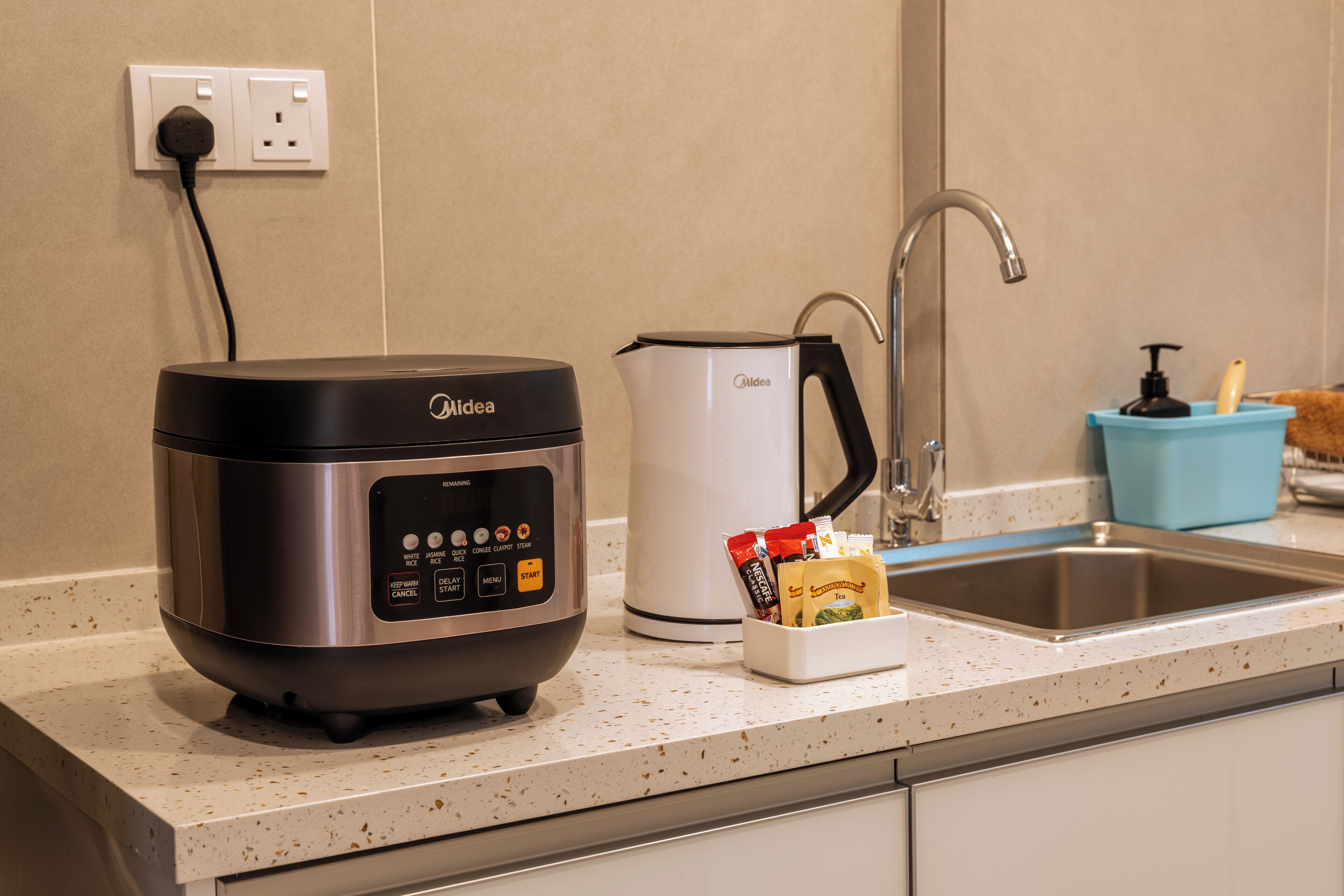 A kitchen with a rice cooker, a coffee maker, and a soap dispenser on the counter.