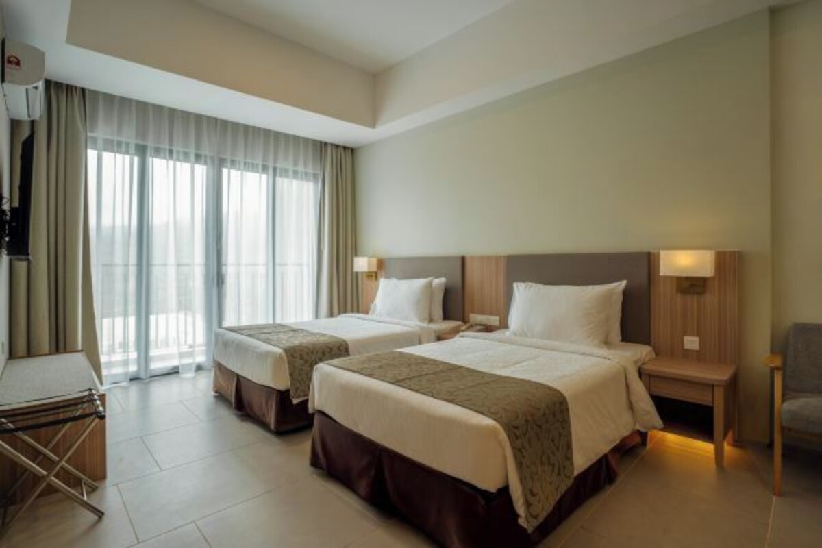 A hotel room with two beds, a desk, and a chair.