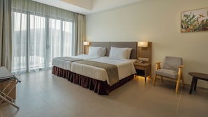 A hotel room with a large bed, a chair, a desk, and a painting on the wall. - Zenith Suites Cameron (Tanah Rata)