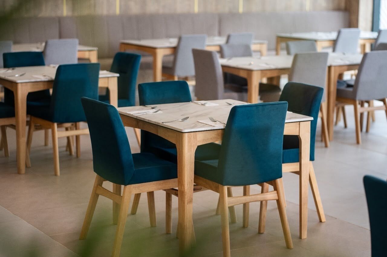 Un ristorante con diversi tavoli e sedie, disposti in un ambiente ampio.
