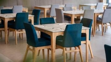 Un ristorante con diversi tavoli e sedie, disposti in un ambiente ampio.