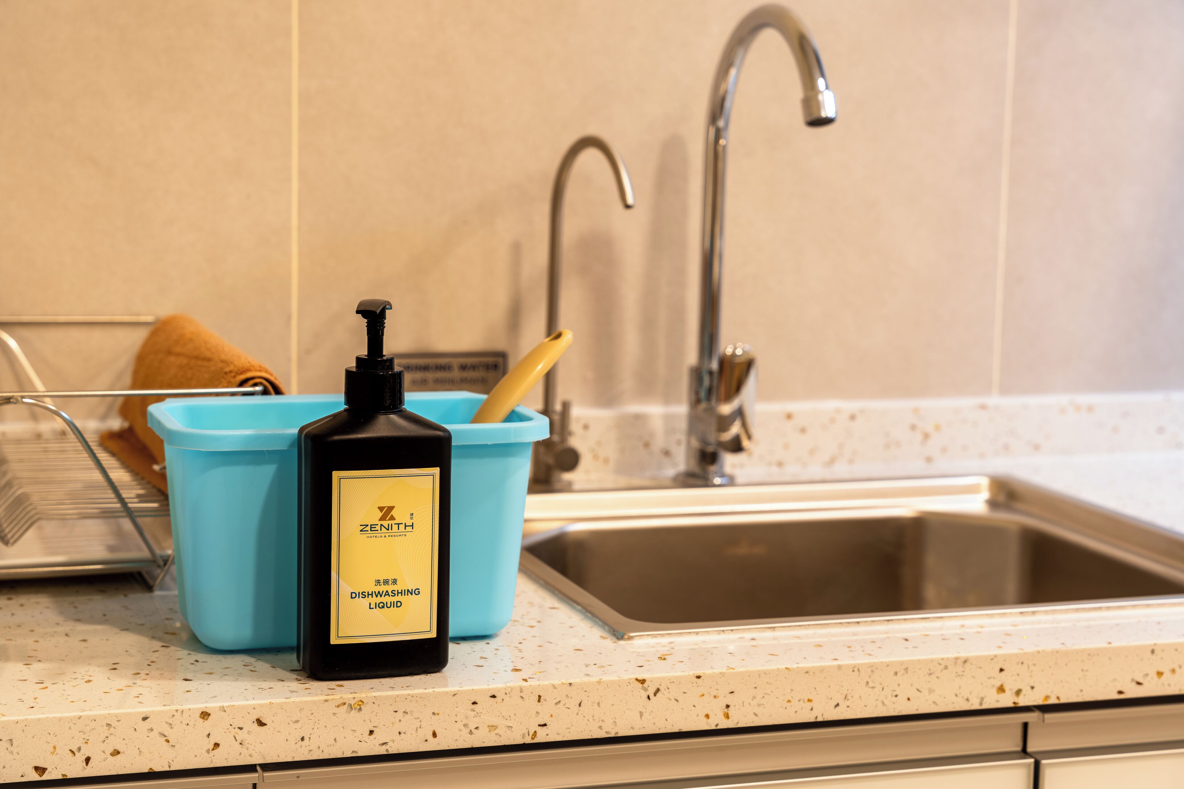 A kitchen with a sink, a blue container, and a bottle of dishwashing liquid.