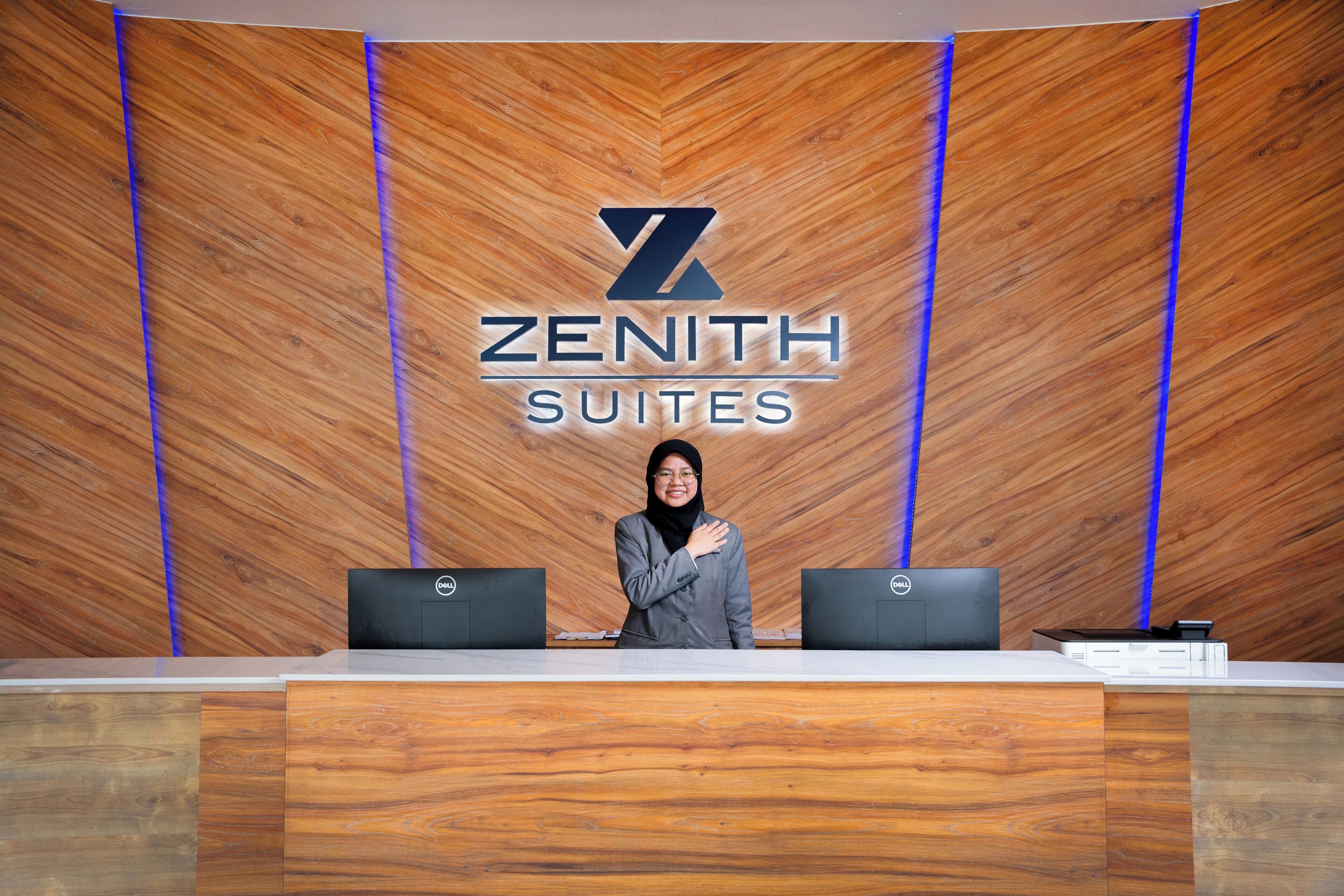 A reception desk with a wooden backdrop and the logo "ZENITH SUITES".