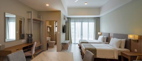 A hotel room with a dining area, two beds, a TV, and a ceiling fan.