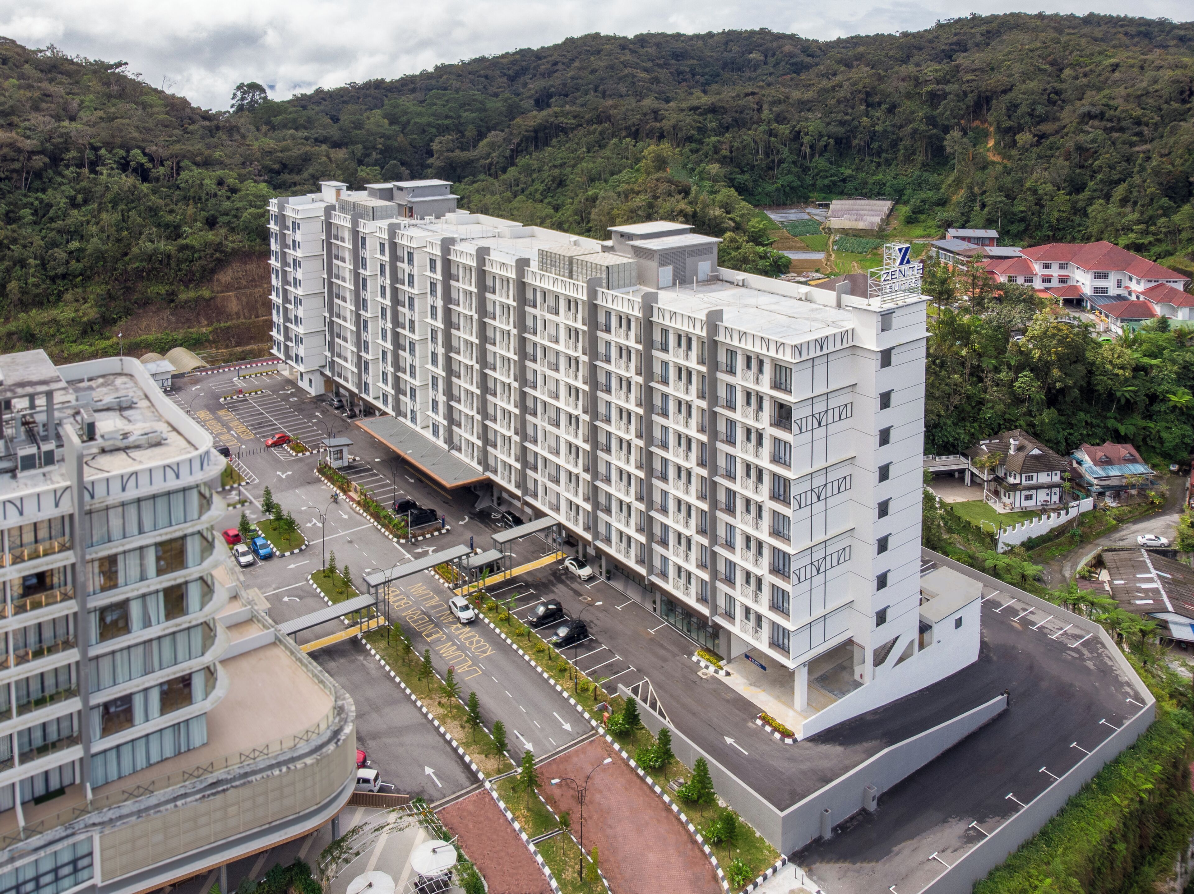 Un hotel de varios pisos con un diseño moderno, que cuenta con un patio central y estacionamiento.