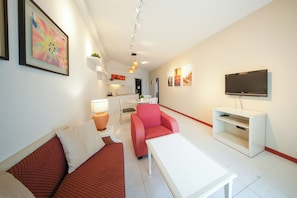 Apartamento executivo, sacada, vista para o mar | Área de estar | TV