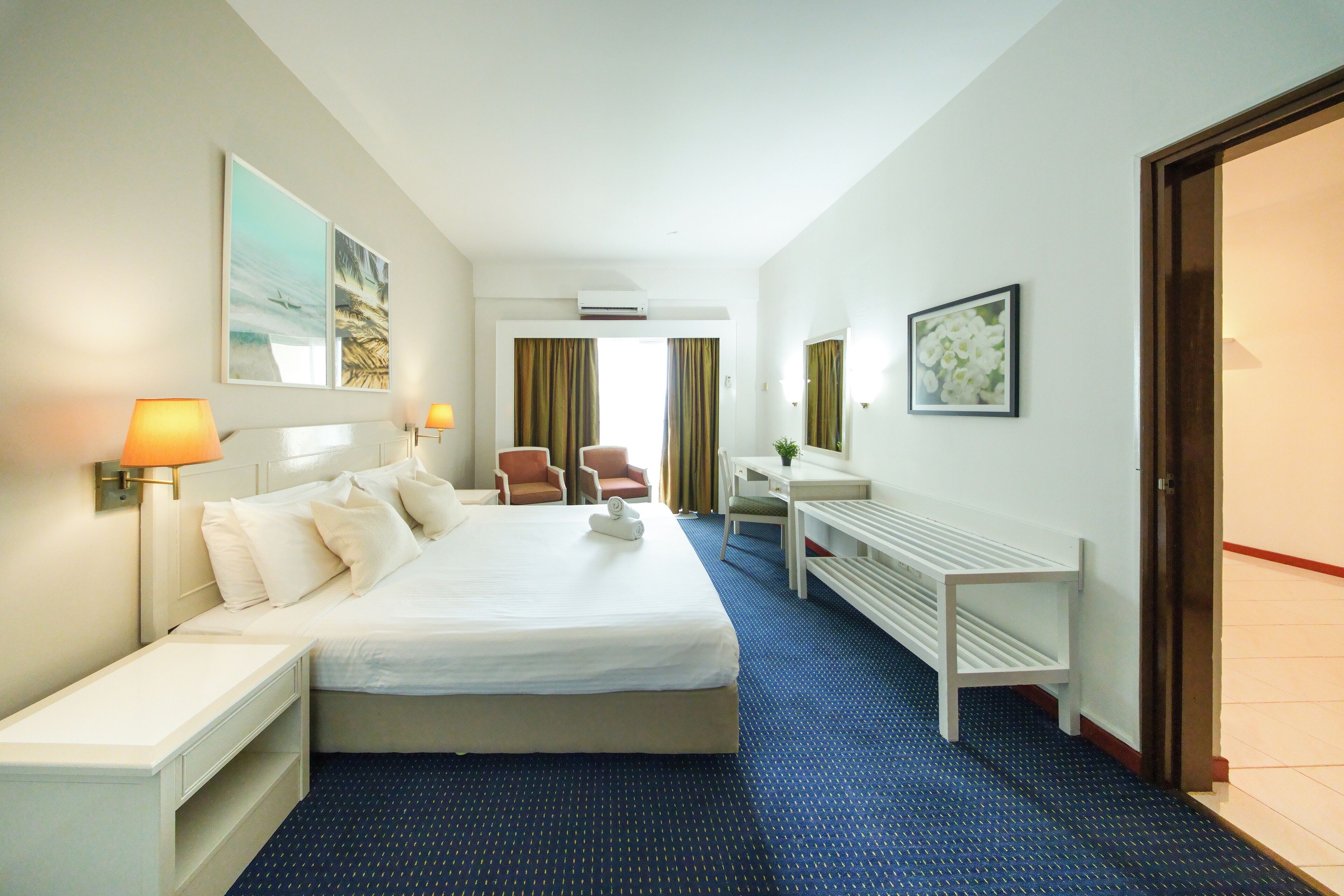 Una habitación de hotel con una cama grande, mesitas de noche, un escritorio y una silla.