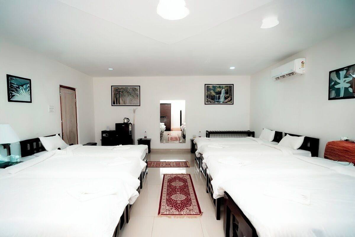 Habitación de hotel con dos camas, alfombra roja y obras de arte en las paredes.