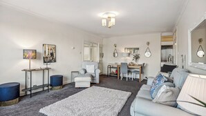 A modern living room with a grey sofa, a white rug, and a dining area with a table and chairs. - Spacious2br-balcony-parking-25mincentrallondon (London)