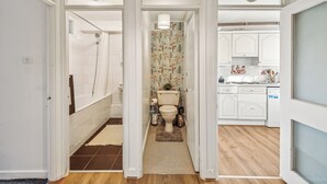 A narrow hallway leading to a bathroom and a kitchen area with white cabinets and a tiled backsplash. - Spacious2br-balcony-parking-25mincentrallondon (London)