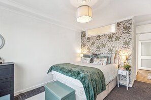 A bedroom with a bed, a nightstand, a dresser, and a ceiling light.