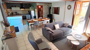 Ein modernes Wohnzimmer mit einem grauen Sofa, einem Esstisch und einer Küche im Hintergrund.