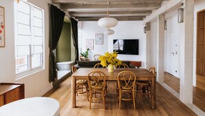 A dining area with a wooden table, wicker chairs, and a vase of yellow flowers. - Maison Hubert (Bordeaux)