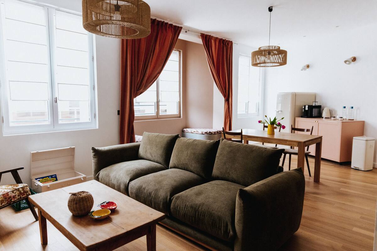 A cozy living room with a sofa, wooden coffee table, and a dining area with a table and chairs.