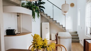 A modern kitchen with a wooden table, a coffee machine, and a vase of yellow flowers. - Maison Hubert (Bordeaux)