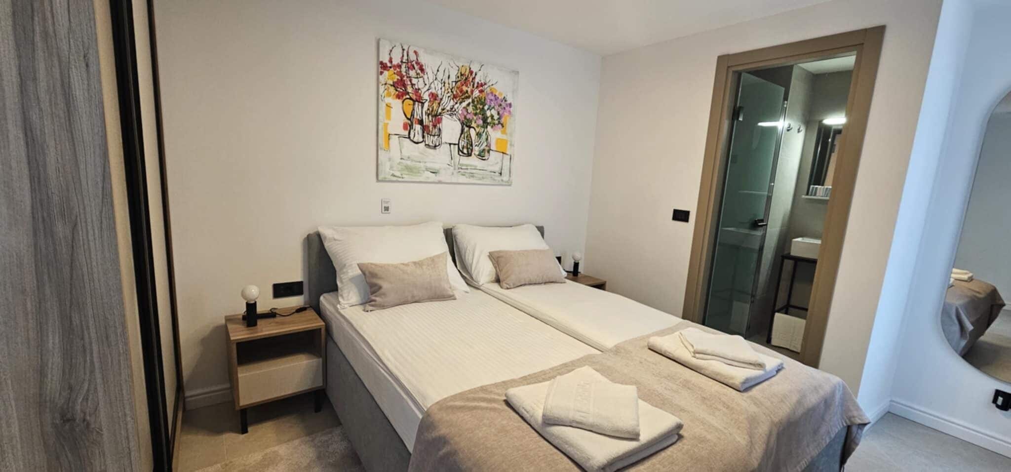 Un lit double avec une tête de lit, une table de chevet et un tableau accroché au mur.