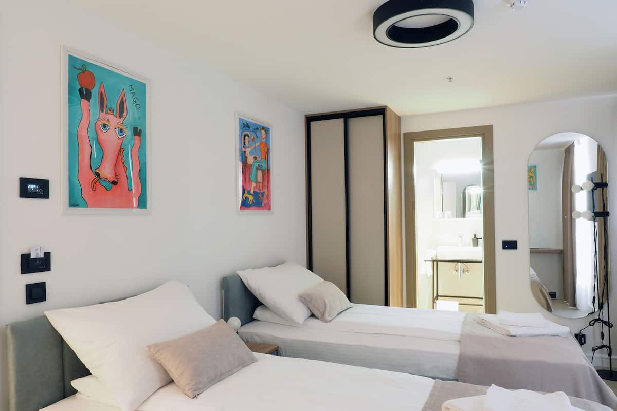 A hotel room with two beds, a large mirror, and artwork on the walls.