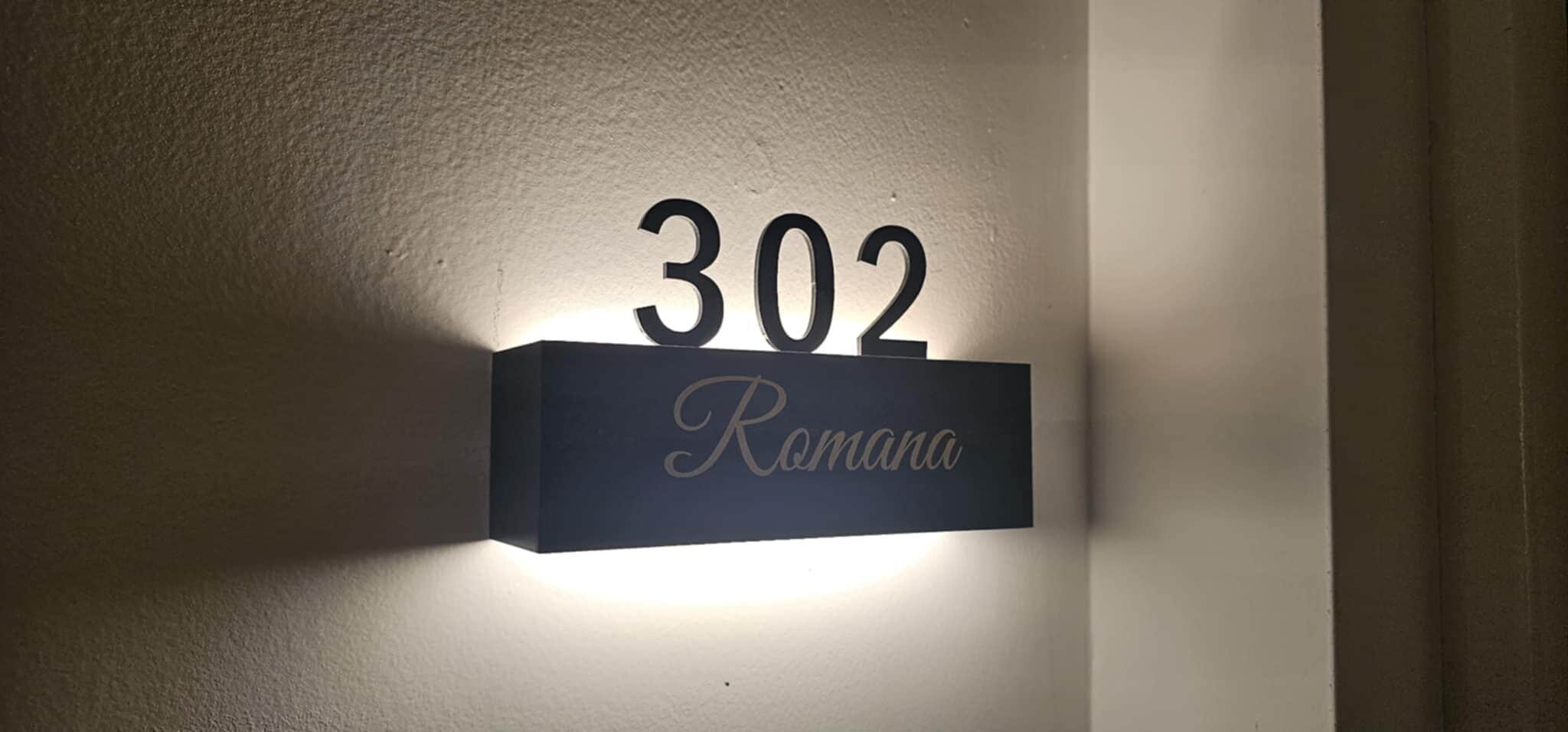 A wall-mounted sign with the number 302 and the name "Romana" on it.