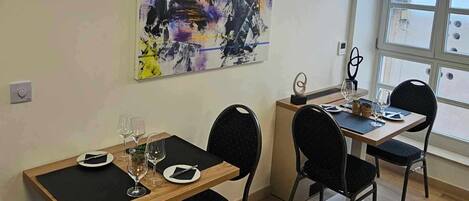 A dining area with two tables, black chairs, and a large abstract painting on the wall.
