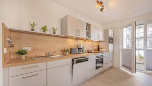 Una cocina moderna con armarios blancos, encimera de madera y electrodomésticos integrados.