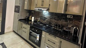 A kitchen with stainless steel appliances, a black countertop, and beige cabinetry.