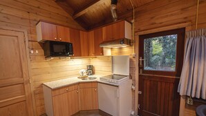 Een kleine keuken met houten kastjes, een magnetron, een fornuis en een spoelbak.