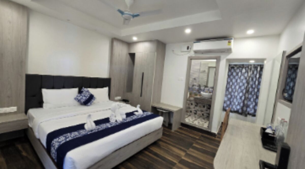 Une chambre d’hôtel moderne dotée d’un grand lit, d’une table de chevet, d’une armoire et d’une salle de bain avec douche et toilettes.