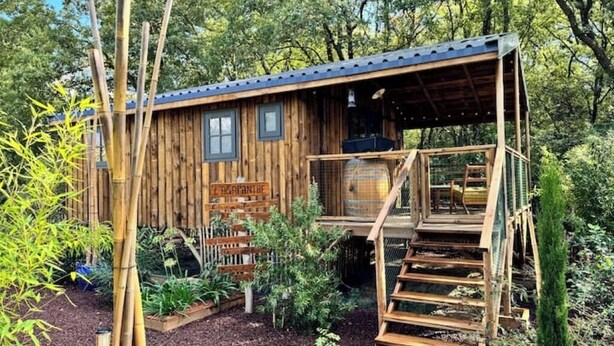 A wooden cabin with a covered porch and a staircase leading to a deck. - Comfortable wooden cabins for rent (heating & air-conditioning). (Clermont-l'Hérault)