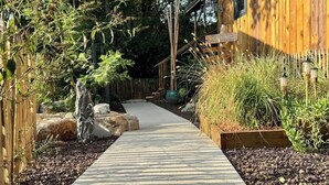 A pathway leading to a wooden house with a garden. - Comfortable wooden cabins for rent (heating & air-conditioning). (Clermont-l'Hérault)