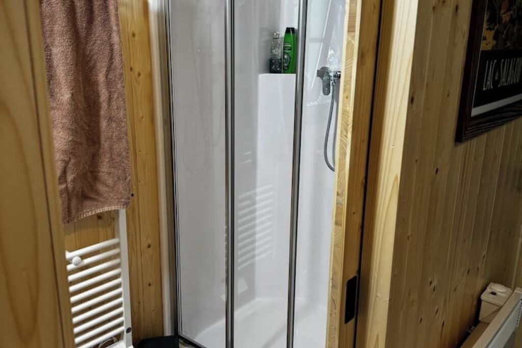 A wooden interior with a glass shower enclosure, a towel hanging on the wall, and a framed picture.