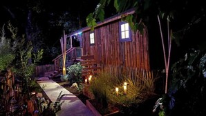 A wooden cabin with a porch, a staircase, and a pathway leading to the entrance. - Comfortable wooden cabins for rent (heating & air-conditioning). (Clermont-l'Hérault)