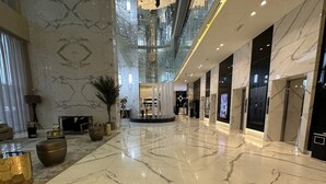 A spacious lobby with marble flooring, a central seating area, and a modern ceiling design. - Luxury Apartment in DAMAC Towers (Riyadh)