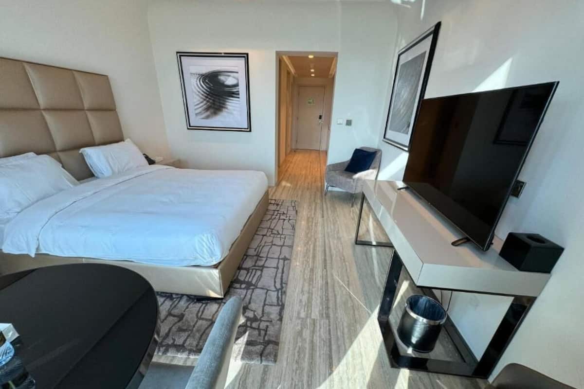 Habitació d'hotel moderna amb un llit gran, un escriptori amb televisió de pantalla plana i una petita zona de seients.
