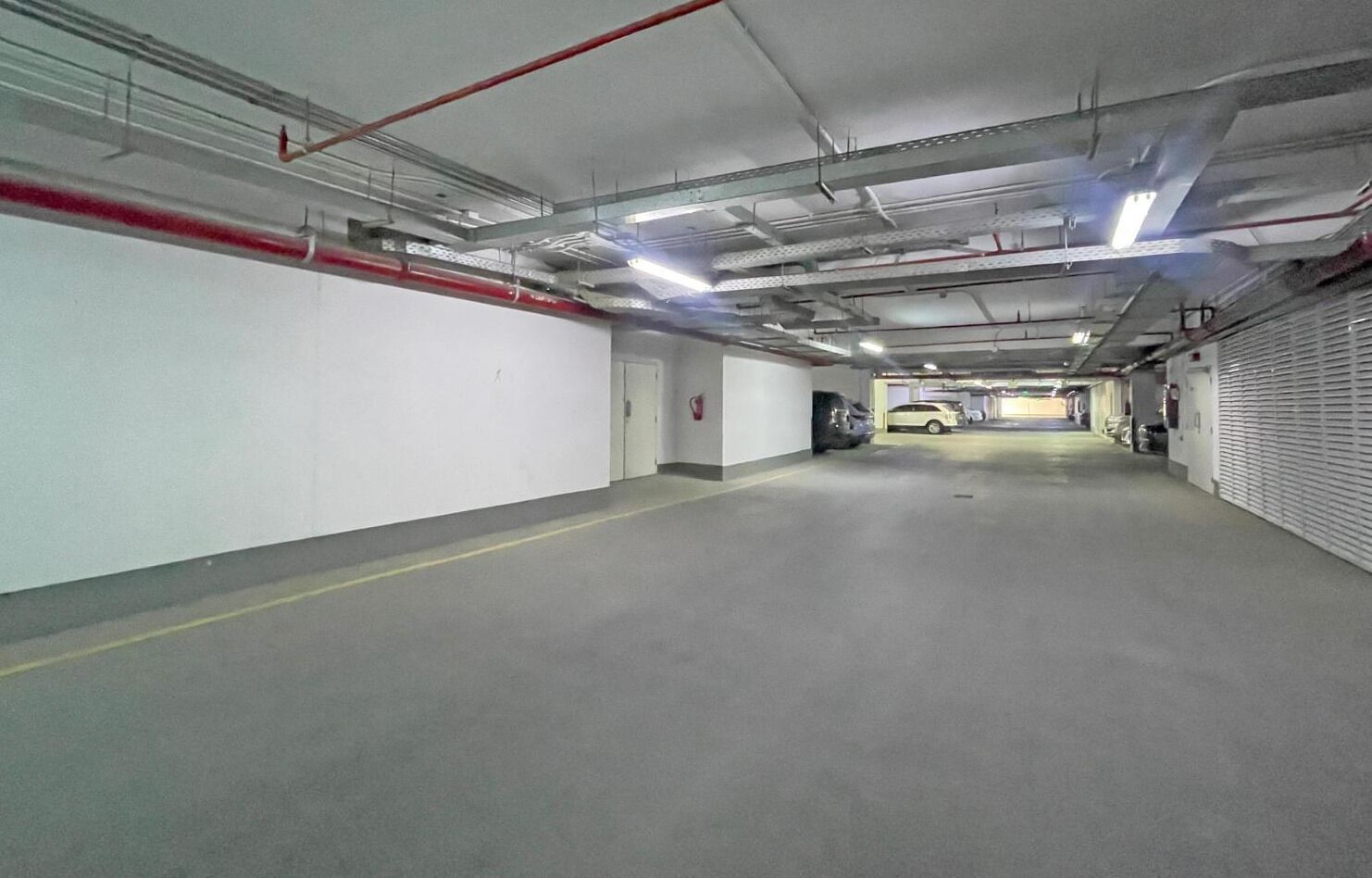 A clean, well-lit parking garage with white walls and a concrete floor.