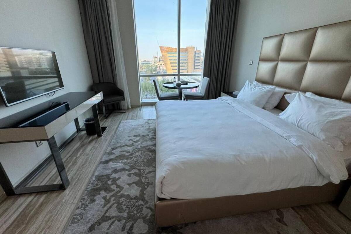 Habitació d'hotel amb un llit gran, televisió, escriptori i vista a la ciutat per la finestra.