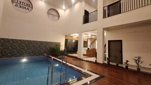 A hotel lobby with a swimming pool, a reception desk, and a staircase. - Hotel Aries Pushkar (Pushkar)