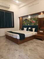 Un dormitorio moderno con una cama grande, una mesita de noche, un aire acondicionado de pared y un mural de paisaje tropical.
