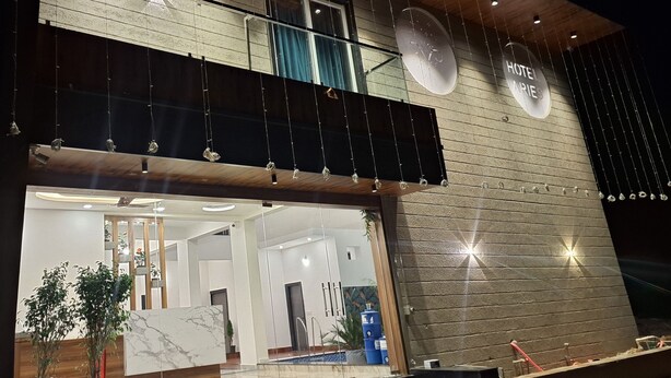 A modern hotel with a large glass entrance, a wooden upper floor, and a sign indicating it is a hotel. - Hotel Aries Pushkar (Pushkar)