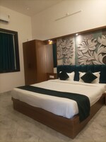 A hotel room with a large bed, a wardrobe, and a decorative wall panel.