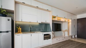 A modern kitchen with white cabinetry, a built-in oven, and a stainless steel refrigerator. - Saturn- Vinhomes Skylake Apartment (Hanoi)
