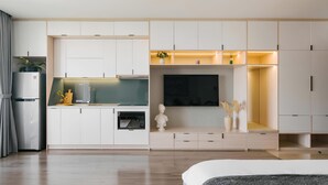 A modern, minimalist bedroom with a large bed, a TV, and built-in storage cabinets. - Saturn- Vinhomes Skylake Apartment (Hanoi)