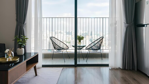 A modern living room with a balcony, a dining table, two chairs, a sofa, and a TV. - Saturn- Vinhomes Skylake Apartment (Hanoi)