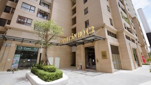A multi-story hotel with a modern facade, a prominent entrance with a glass canopy, and a sign indicating the name and location. - Saturn- Vinhomes Skylake Apartment (Hanoi)
