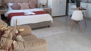 Een slaapkamer met een bed, nachtkastje, dressoir en een kitchenette.