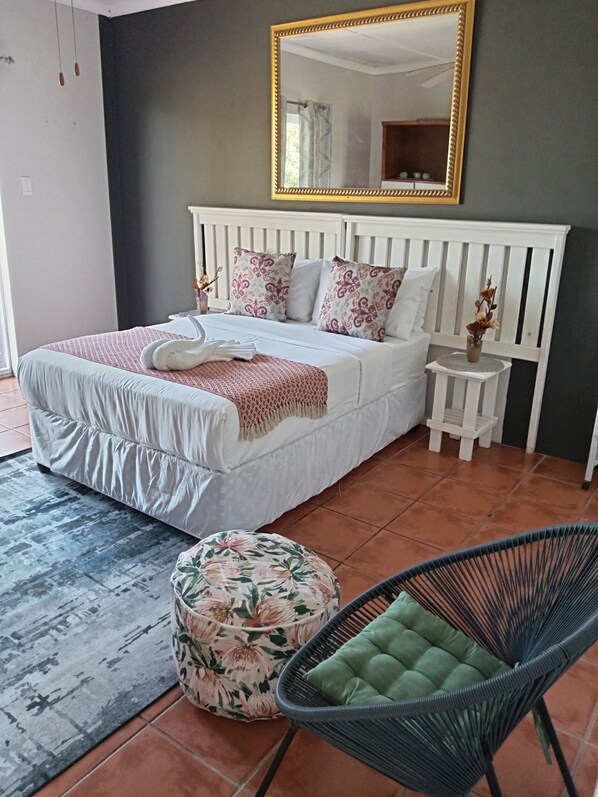 A bedroom with a bed, a nightstand, a chair, and a mirror.