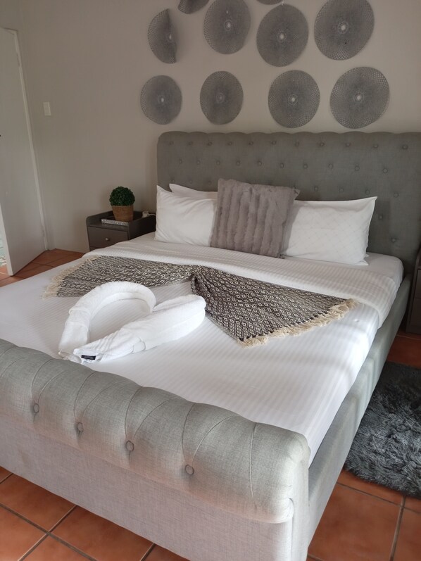 A neatly made bed with a grey headboard, white bedding, and a patterned throw. - Arbour Lodge (East London)