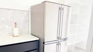 Une cuisine moderne dotée d’un réfrigérateur en acier inoxydable, d’un plan de travail blanc et d’un dosseret en carreaux hexagonaux.